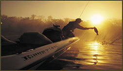 Angler casting from a Ranger bass boat at sunset